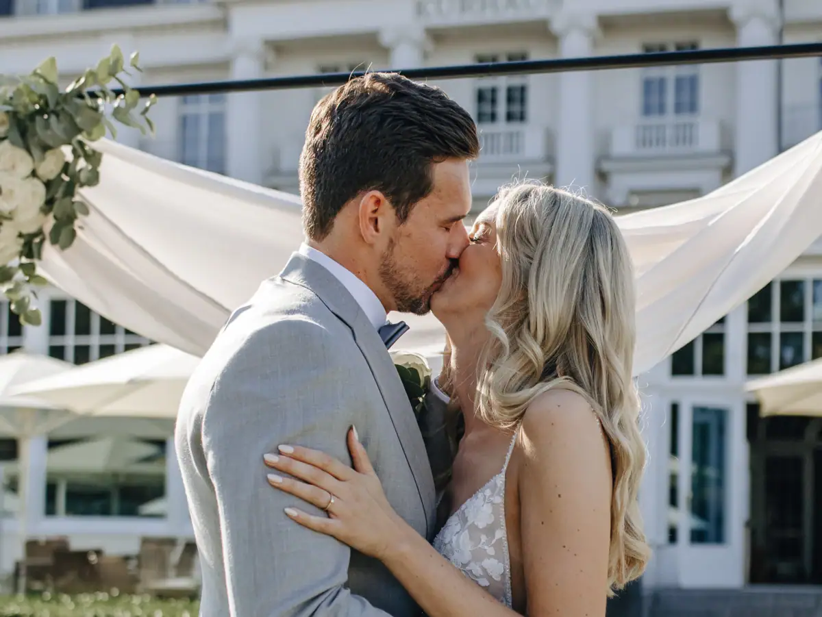 Hochzeitspaar Travemünde Ein Mann und eine Frau küssen sich im Freien, die Frau trägt ein Hochzeitskleid.