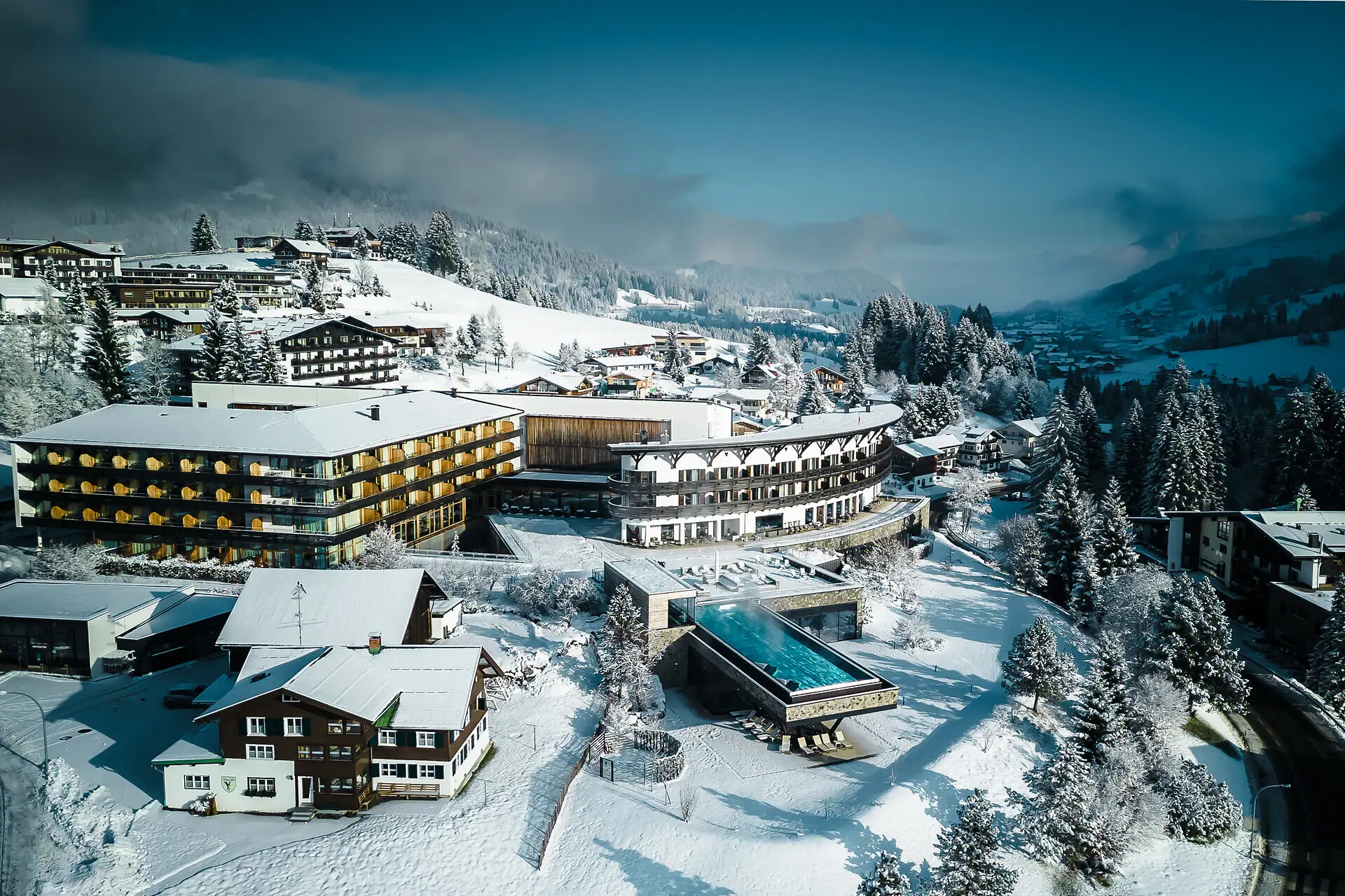 Winter view of A-ROSA Ifen Hotel nestled in the snowy Kleinwalsertal mountains.