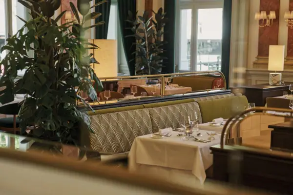 A restaurant interior with tables and chairs next to a window, featuring a Christmas tree.