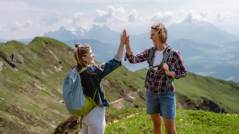 Zwei Frauen geben sich in den Bergen ein High Five.