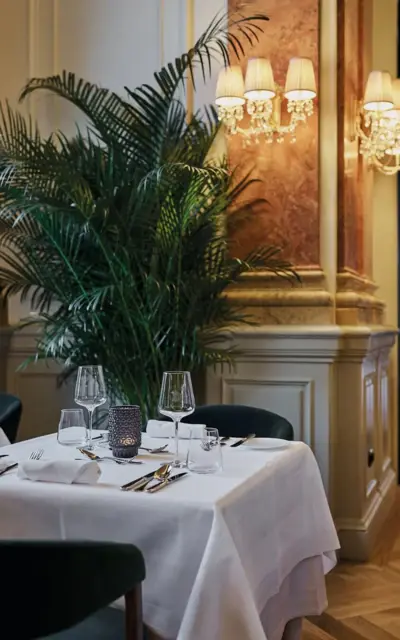 A table set for dinner with a tablecloth and vase as decoration.