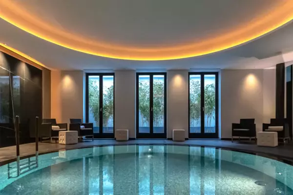 Large indoor swimming pool with a round design, featuring elegant interior elements and a high ceiling.