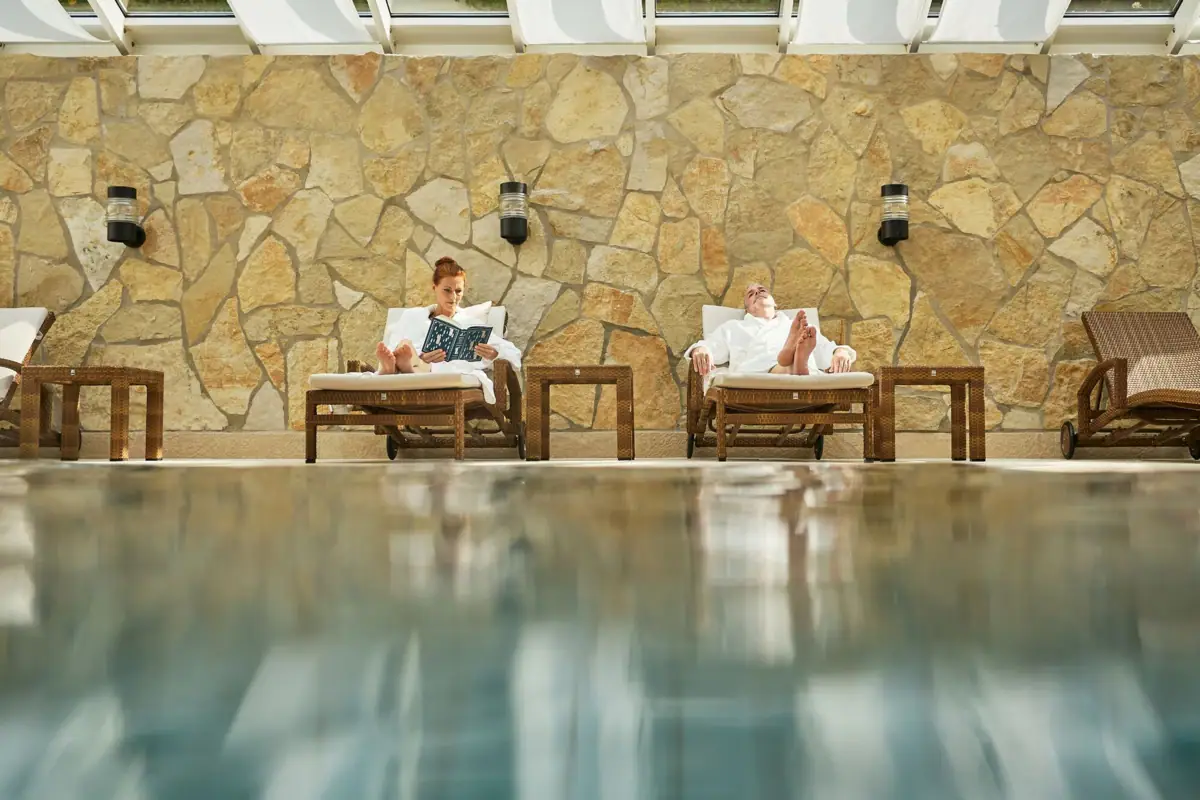 Ein Mann und eine Frau sitzen auf Stühlen am Pool.
