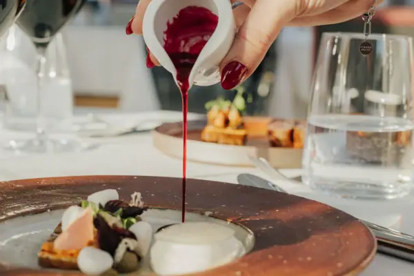 One person pours red sauce onto a plate.