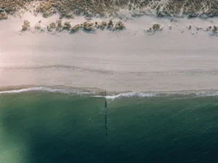 An aerial view of the Baltic Sea, where the sea meets the empty beach with waves.