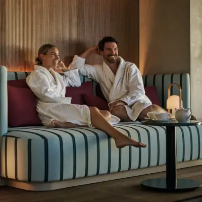 A woman and a man sit in bathrobes in a cosy sitting area at the Day SPA in the Straubing Grand Hotel.