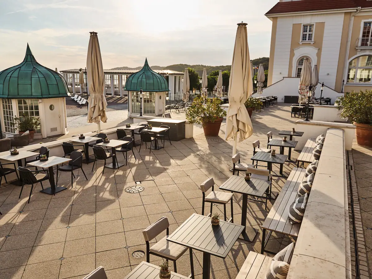 A patio with tables and umbrellas under a clear sky.