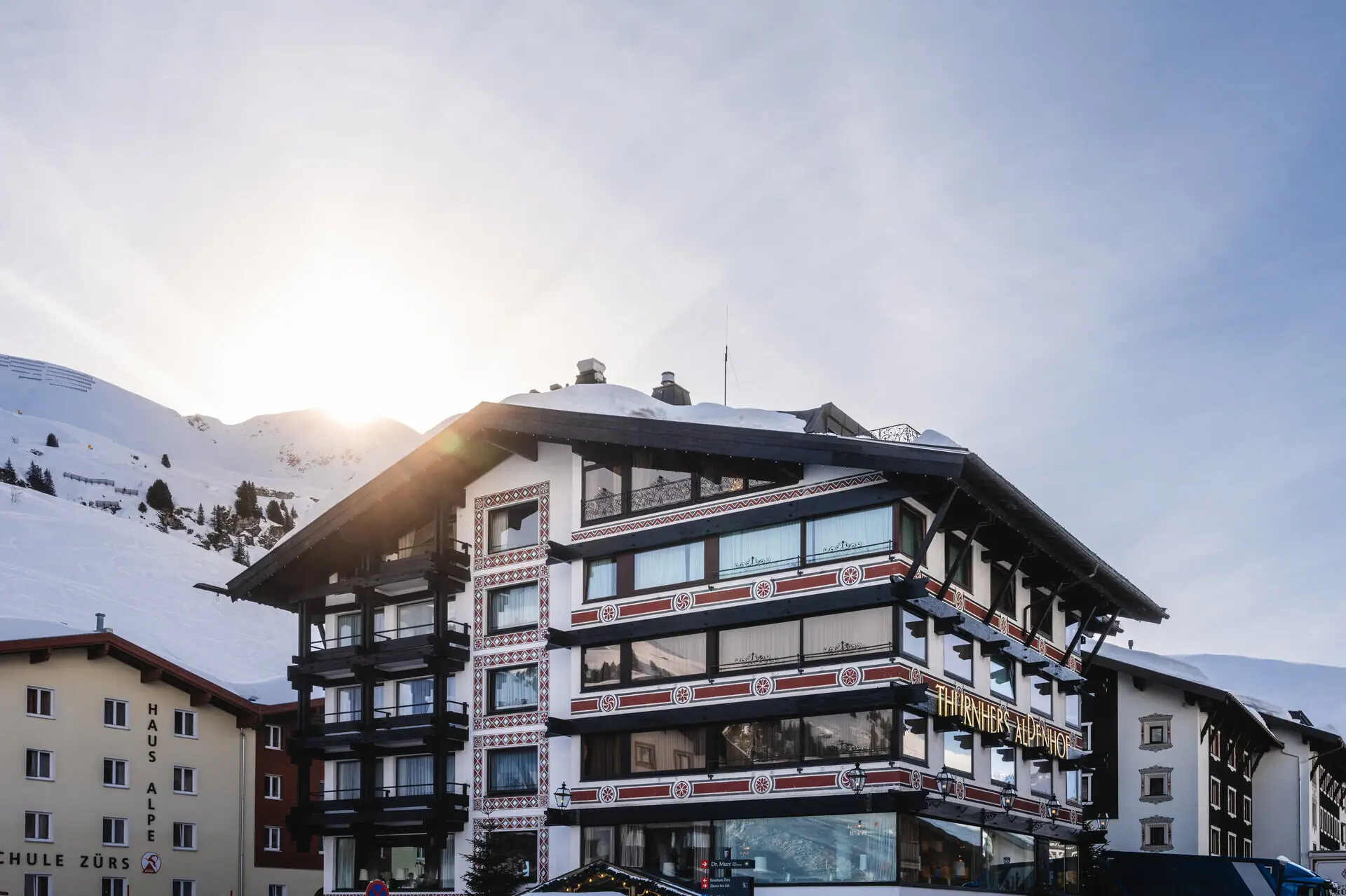 Exterior of Thurnher’s Alpenhof surrounded by snowy peaks of Zürs am Arlberg.