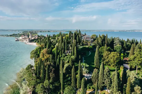 Punta San Vigilio A large green island with trees and a building in the distance.