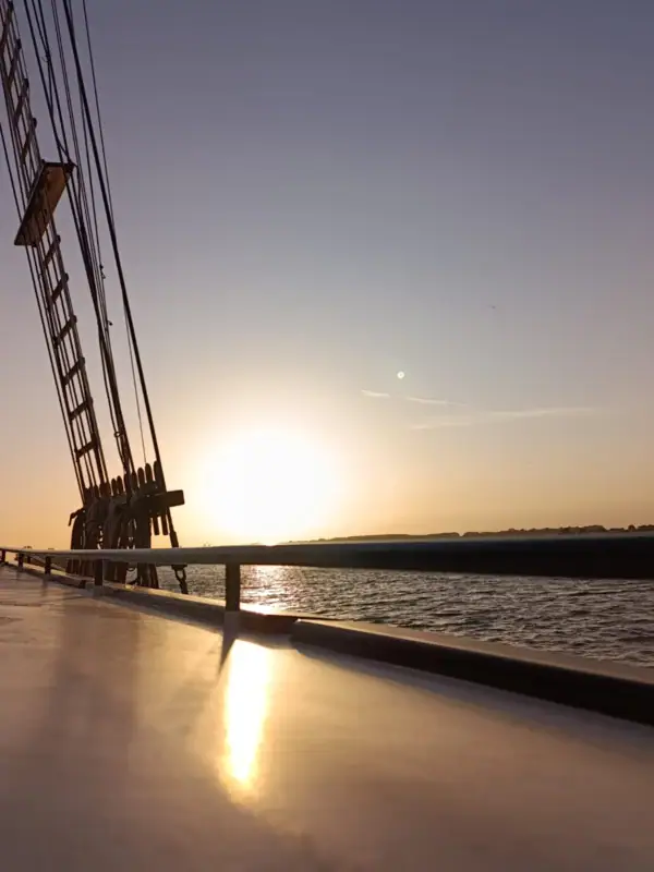 Sonnenuntergang über Wasser mit einer Brücke im Vordergrund.