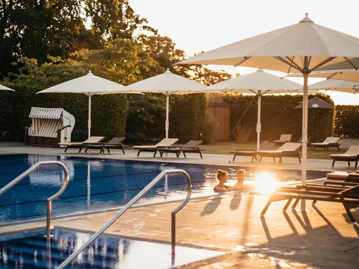 Ein Außenpool mit Sonnenschirmen und Liegestühlen.