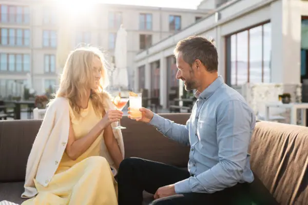 Ein Mann und eine Frau sitzen auf einem Sofa und halten Getränke.