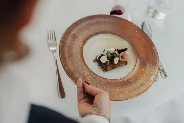 One hand holds a plate of food.