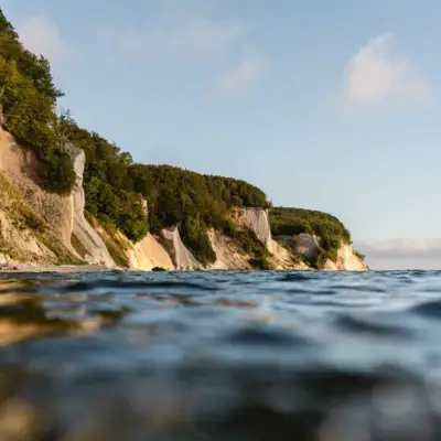 Water with a cliff and trees.