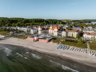 Beach with a large building and chairs on it.