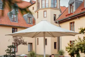 Eine Frau sitzt an einem Tisch unter einem Sonnenschirm im Innenhof.