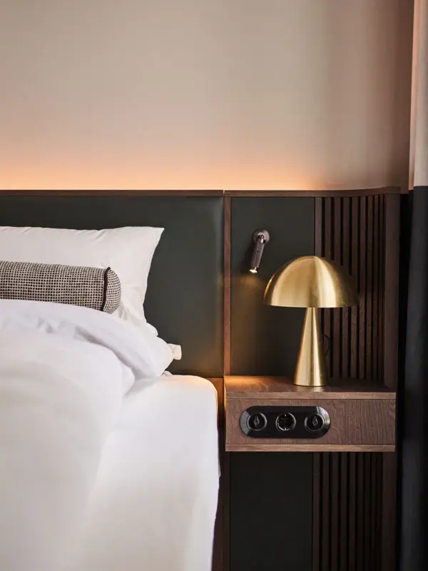 A bed with a gold lamp on a nightstand.