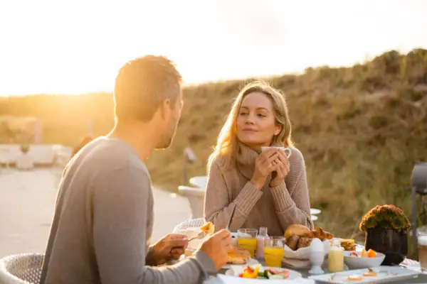 A man and a woman are sitting at a table with food.