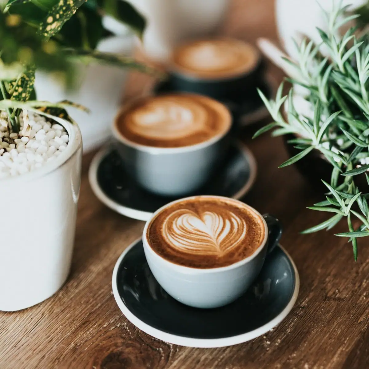 A group of coffee cups with heart-shaped foam designs.