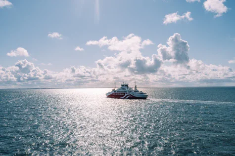 A boat on a calm lake under a partly cloudy sky.