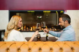 A man and a woman are sitting at a table with glasses of wine.