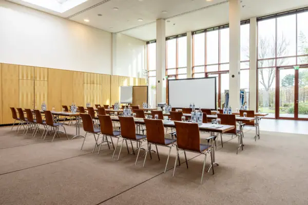 A room at the A-ROSA Travemünde with tables and chairs.