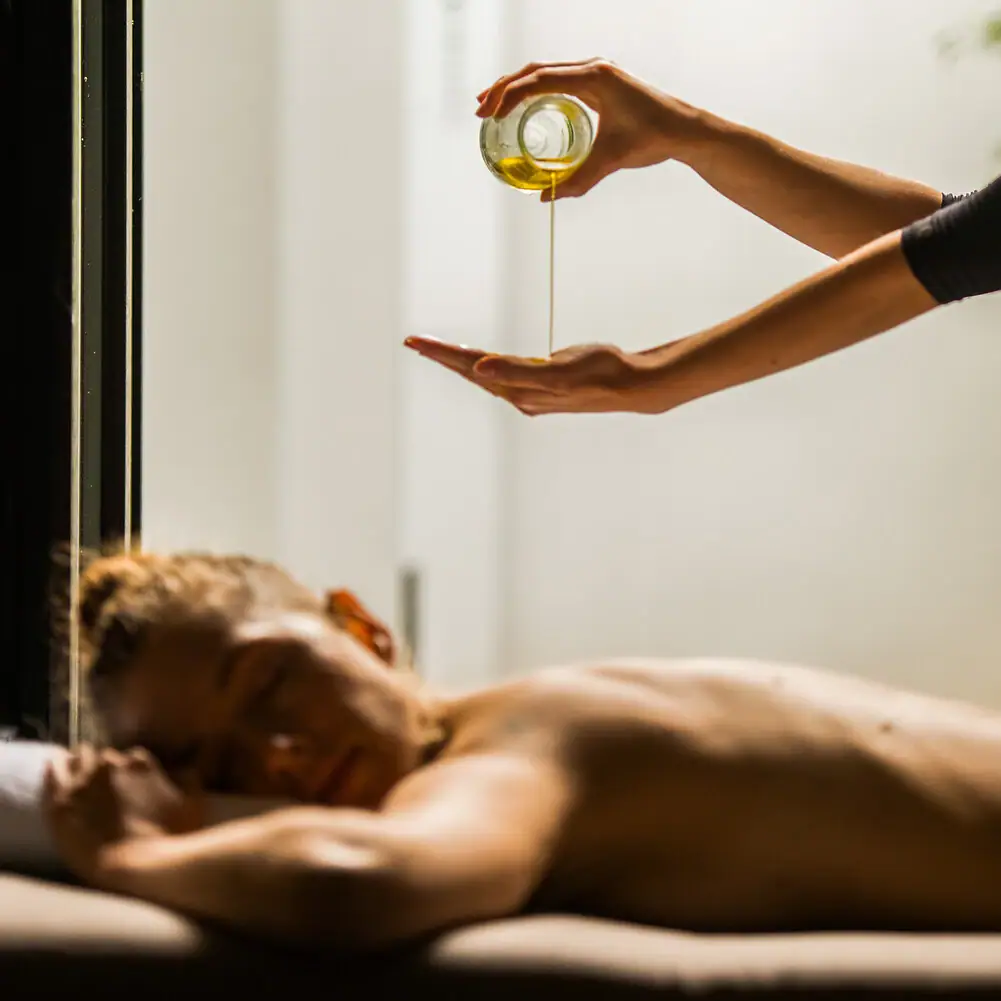 Massage A person pouring oil into another person's hand indoors.