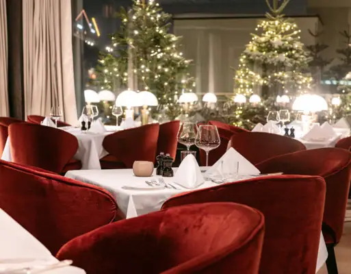 Gastronomy A table set with a white tablecloth and surrounded by red chairs.