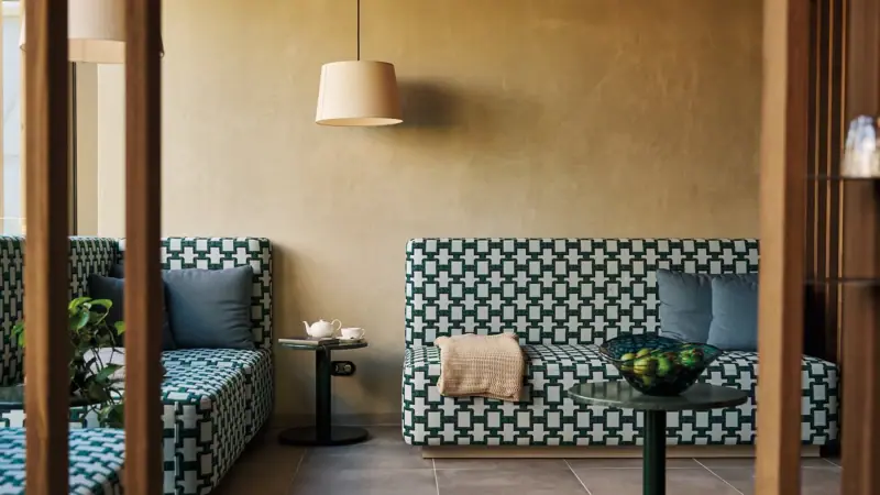 Sofas and a table in a room with a vase and lamp.