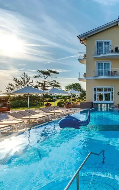 Outdoor pool with sun loungers and a building in the background.