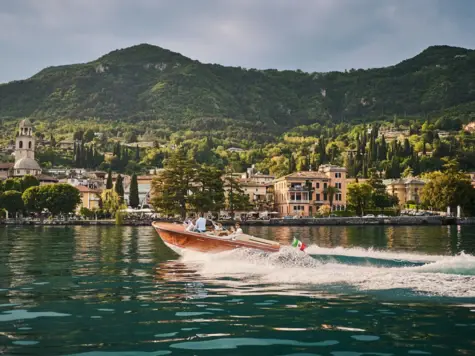 Boat on Lake Garda surrounded by mountains and clouds.