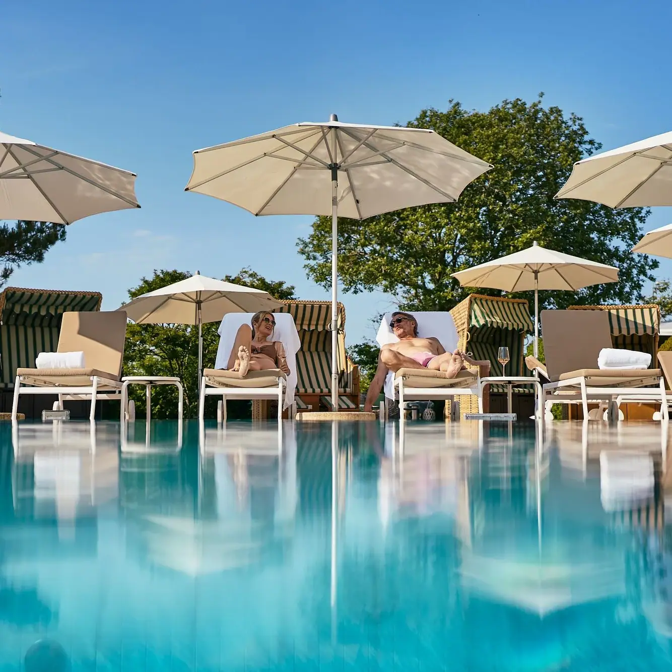 Eine Gruppe von Menschen sitzt auf Stühlen am Pool.