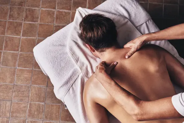A person receiving a back massage with a towel draped over them.