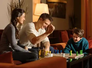 Family sitting on a sofa and playing a board game.