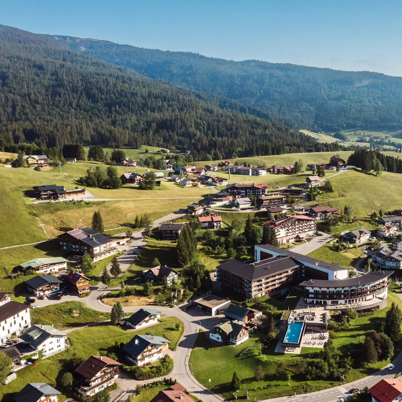 Aerial view of a mountain village surrounded by trees and hills.