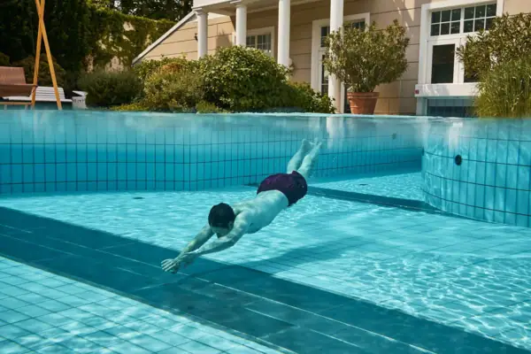 A man swimming in an outdoor pool.