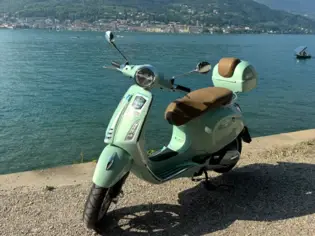 Scooter parked on a sidewalk next to Lake Garda.