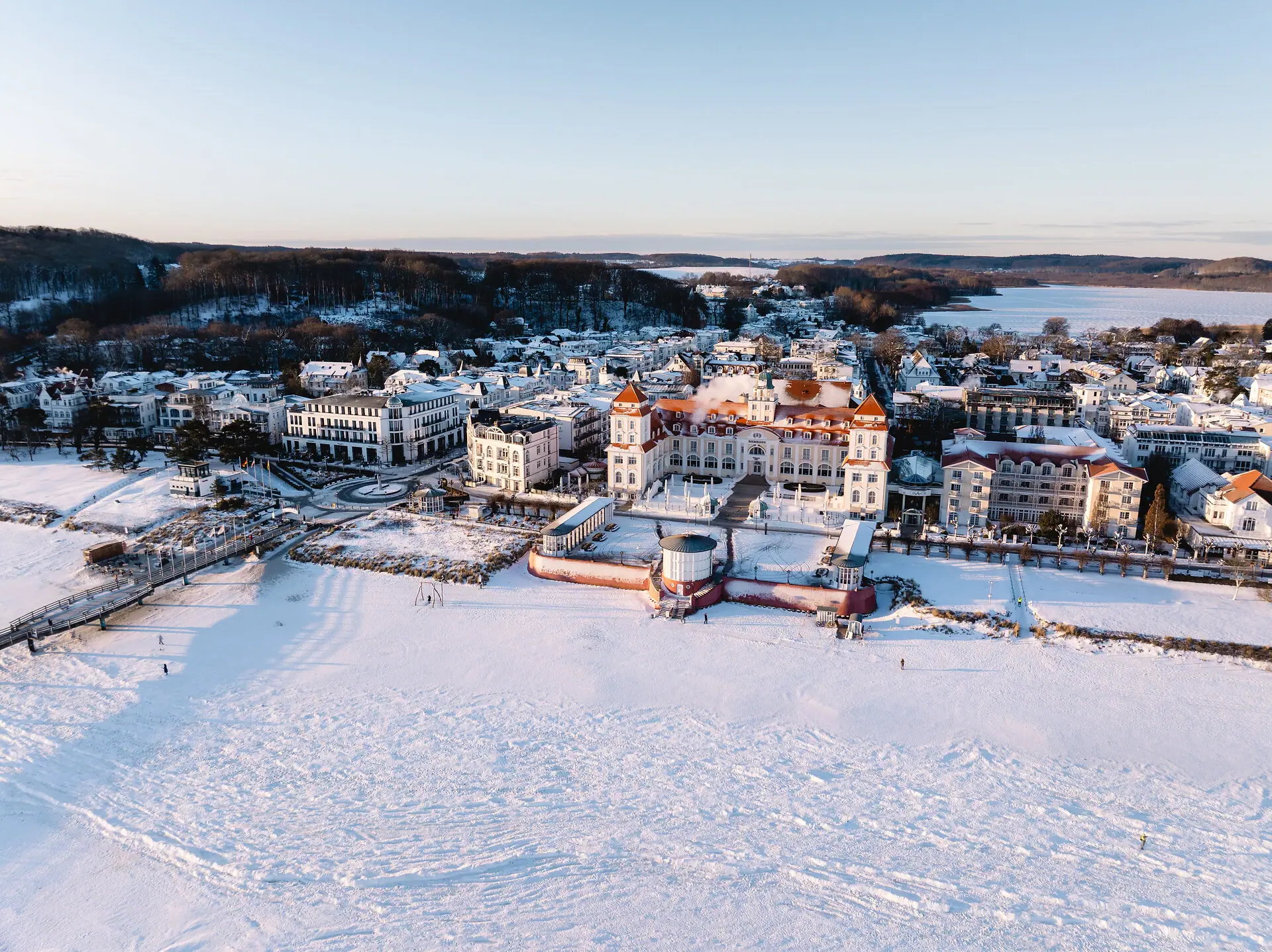 A snow-covered town with buildings and a body of water in winter.