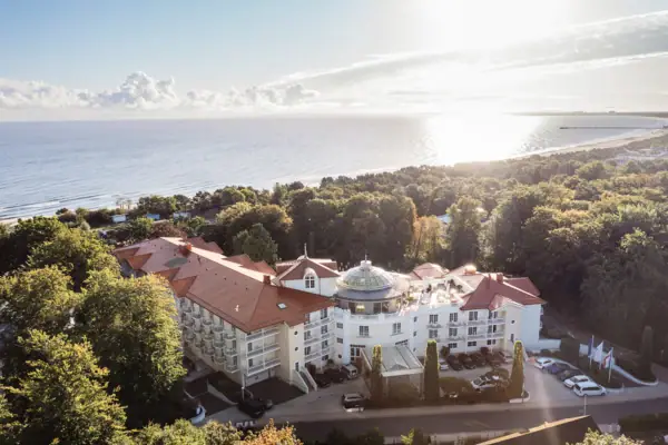 Large building with trees and a body of water in the foreground.