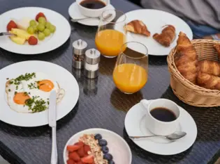 A breakfast table with plates full of food and drinks.