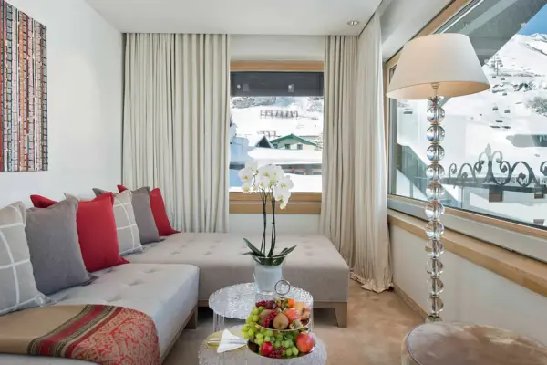 Living room featuring a couch, coffee table, and decorative vase on the table, with a window in the background overlooking snowy mountains.