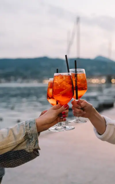 A group of people toast with wine glasses containing orange liquid.