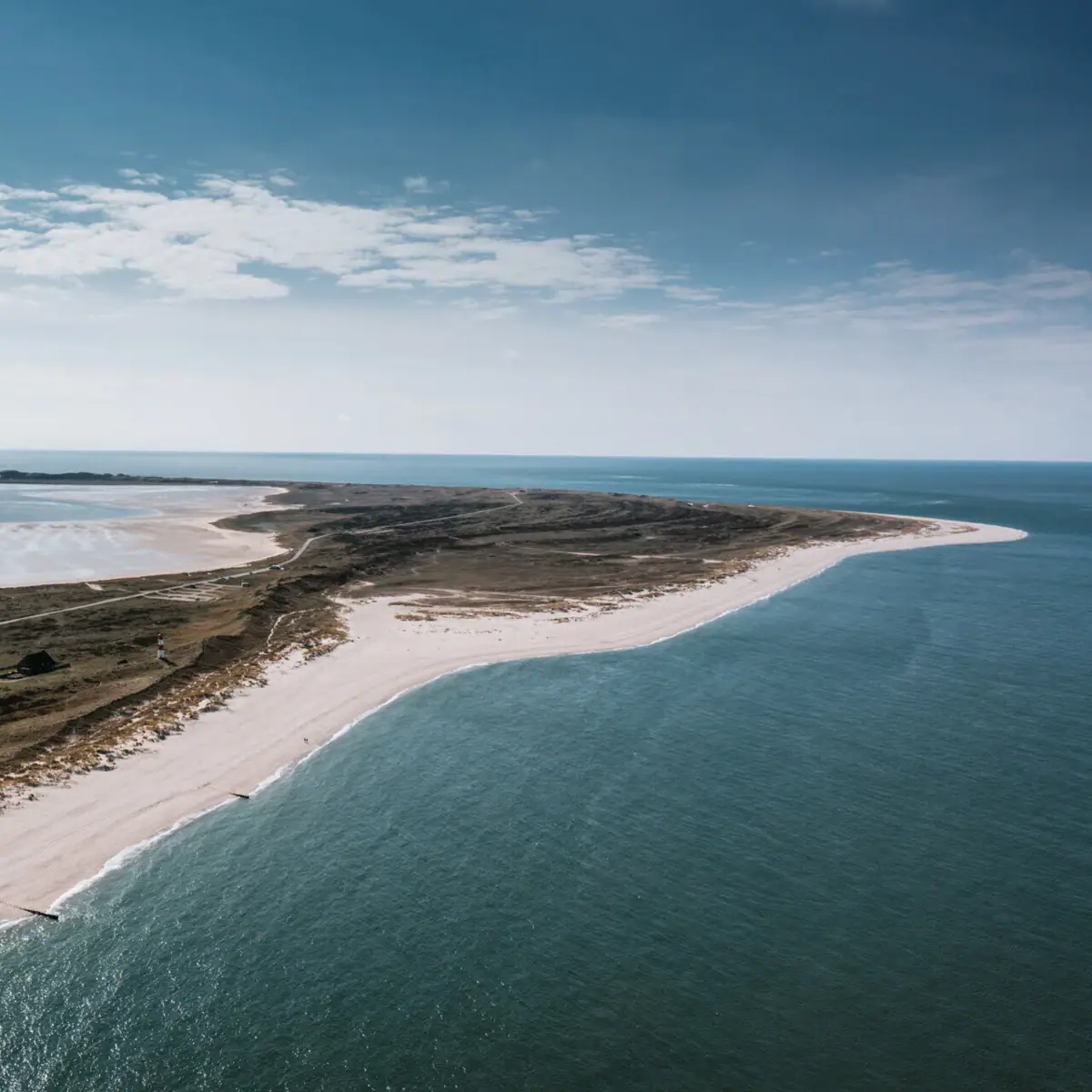 Ein Strand mit Sand und Wasser unter einem bewölkten Himmel.