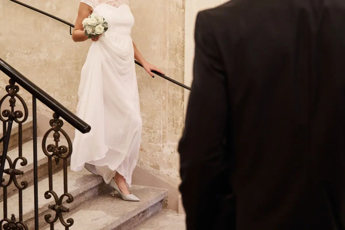 Bride in a white dress holding a bouquet of flowers climbing stairs