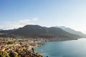 Stadt am Ufer eines Sees mit Bergen im Hintergrund.