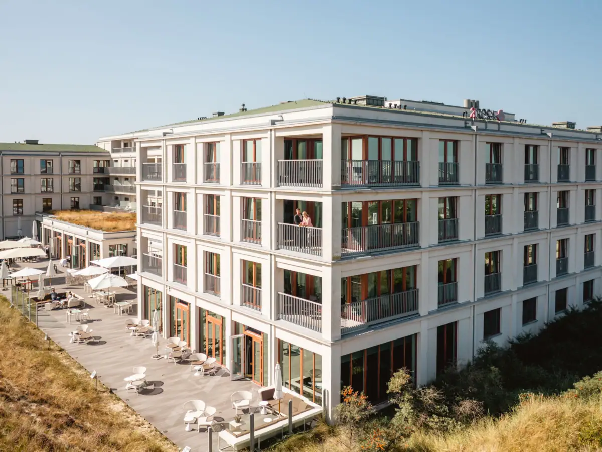 A-ROSA Sylt Das A-ROSA Hotel Sylt mit vielen Fenstern und einer Terrasse.
