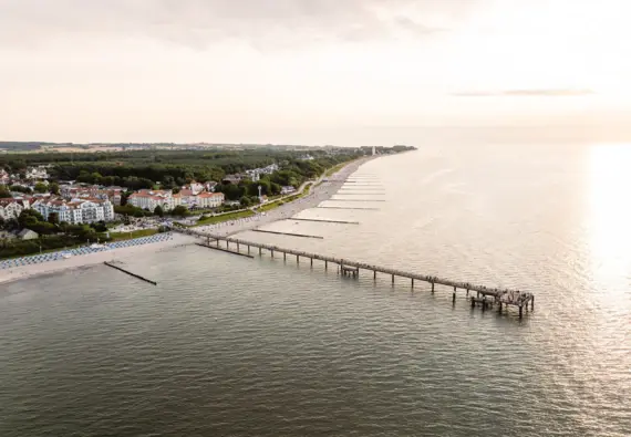 A long jetty leads to a beach with clear skies and calm waters.