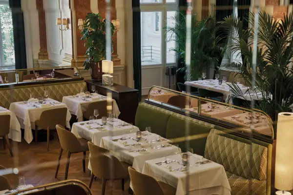 A restaurant interior with tables and chairs, featuring a window and tablecloths.