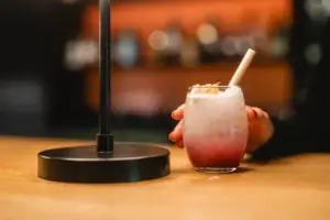 A hand is holding a drink with a straw and cocktail garnish.