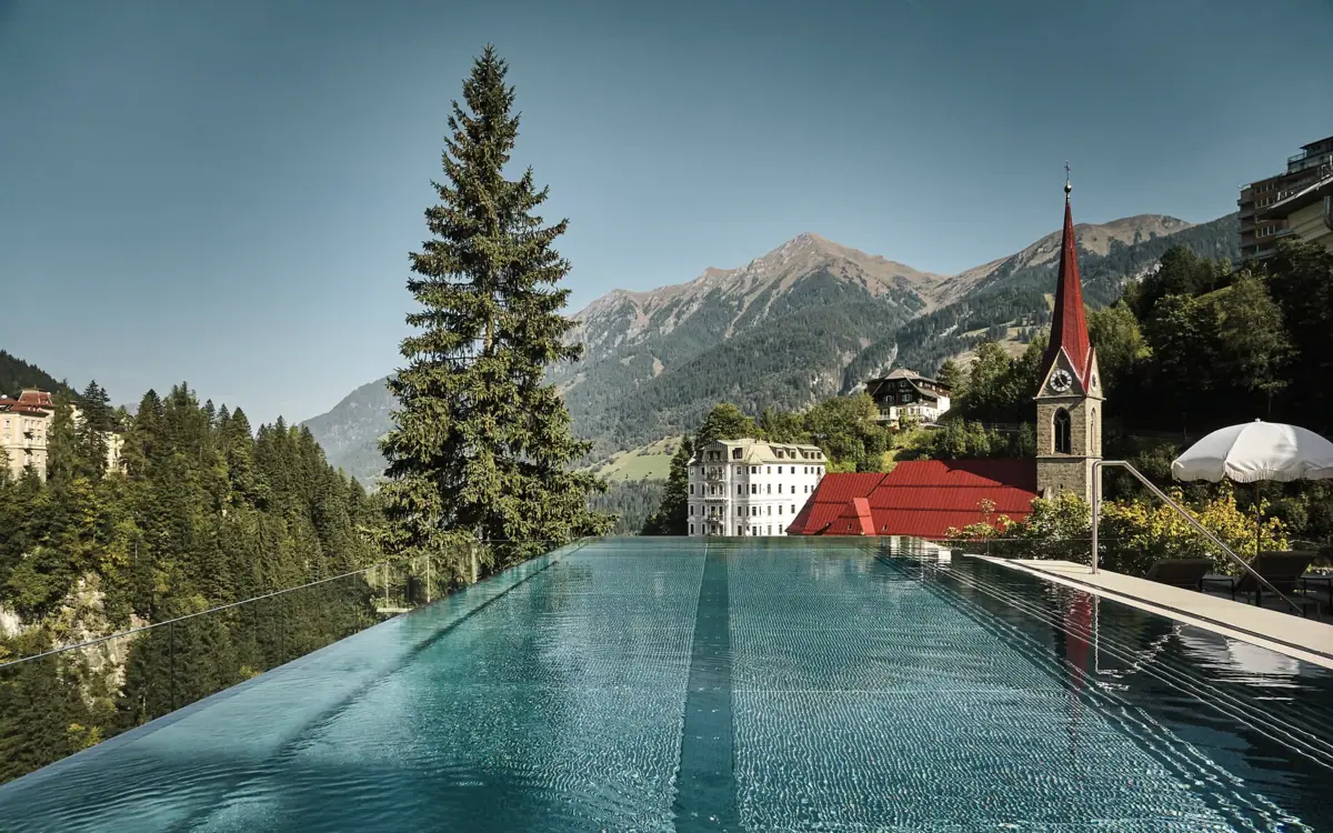 A pool with a building and mountains in the background.